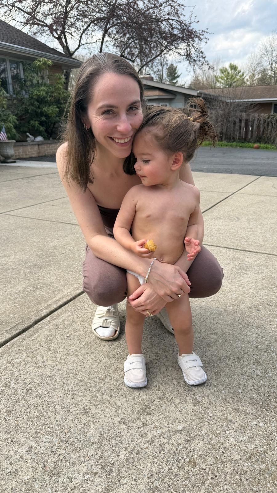 Lauren crouching outside, holding Mila close
