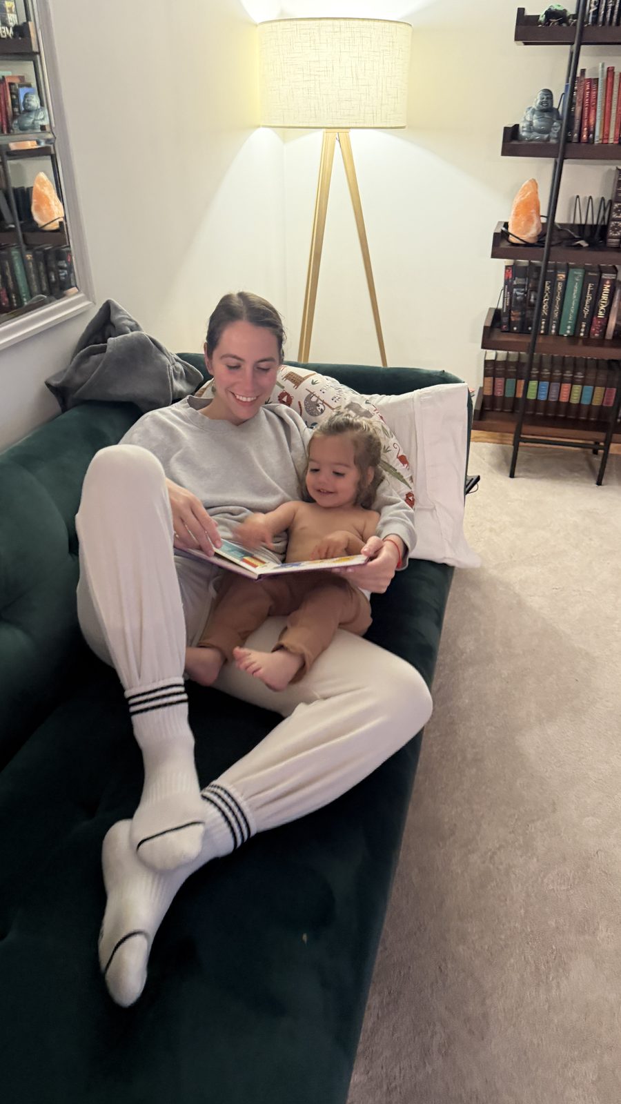 Lauren reading a book to Mila on the green couch