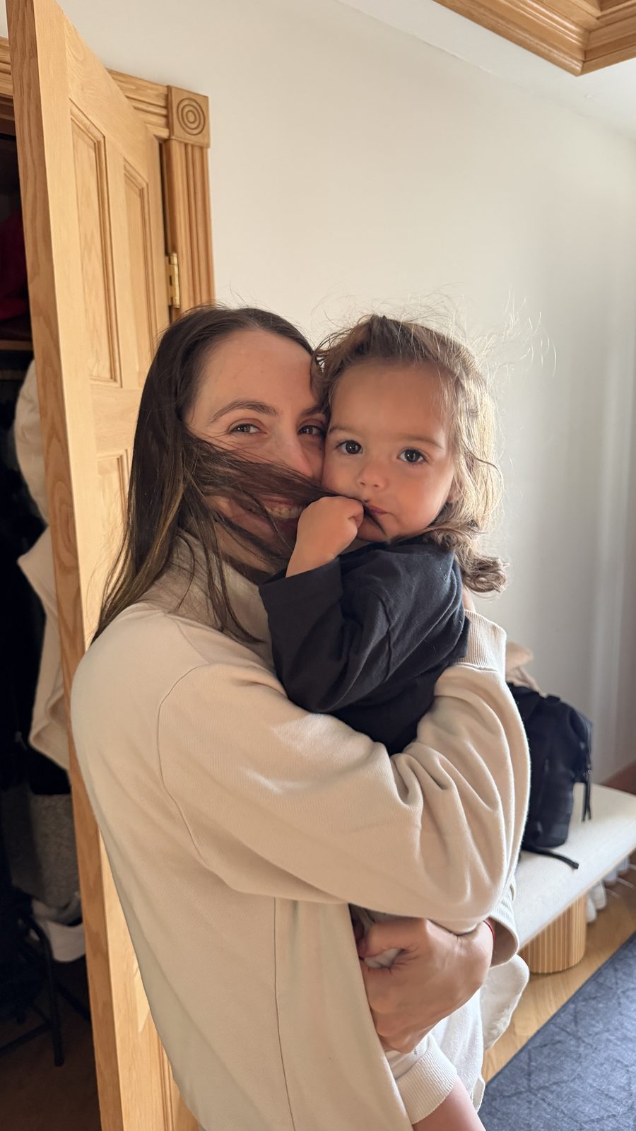 Lauren holding Mila, hair across her face